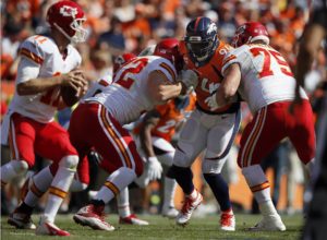 Denver Broncos defensive end DeMarcus Ware (94) is blocked by Kansas City Chiefs tackle Eric Fisher (72) and Mike McGlynn (75) as he eyes Alex Smith(11) during an NFL football game between the Denver Broncos and the Kansas City Chiefs, Sunday, Sept. 14, 2014, in Denver. (AP Photo/Jack Dempsey)