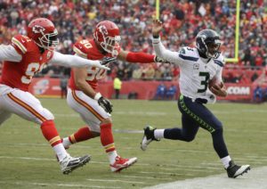 Seattle Seahawks quarterback Russell Wilson, right, runs from Kansas City Chiefs defenders Tamba Hali, left, and Josh Mauga, center, during the first half of an NFL football game in Kansas City, Mo., Sunday, Nov. 16, 2014. (AP Photo/Charlie Neibergall)